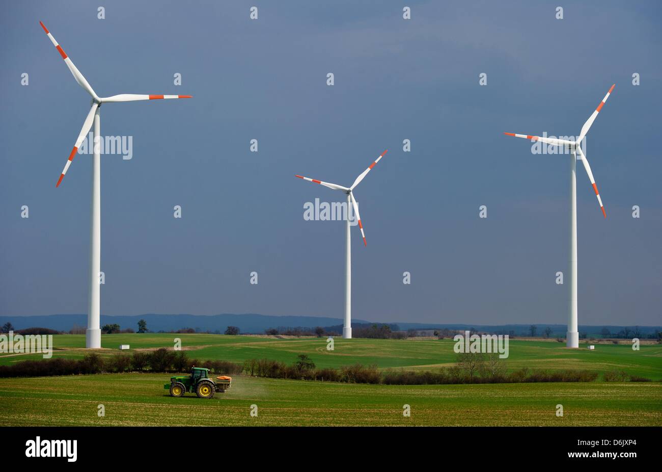 Un agricoltore unità su un campo con le turbine eoliche con un trattore, vicino Angermuende, Germania, 18 aprile 2013. Foto: Patrick Pleul Foto Stock