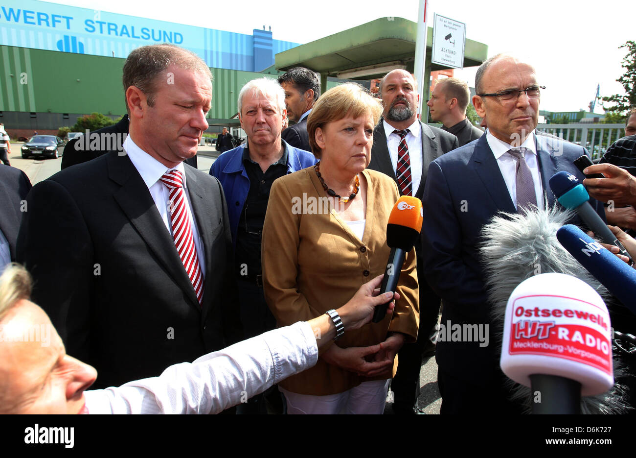 Il cancelliere tedesco Angela Merkel, Premier di Meclemburgo-pomerania Erwin Sellering (R) e Manager di P+S-Werften in Stralsund e Wolgast Ruediger Fuchs (L) dare una dichiarazione all'ingresso del cantiere Volksweft a Stralsund, Germania, 21 agosto 2012. Merkel ha preso parte a una riunione sul futuro della società di costruzione navale, dove i rappresentanti dei media non sono consentiti. Foto Stock