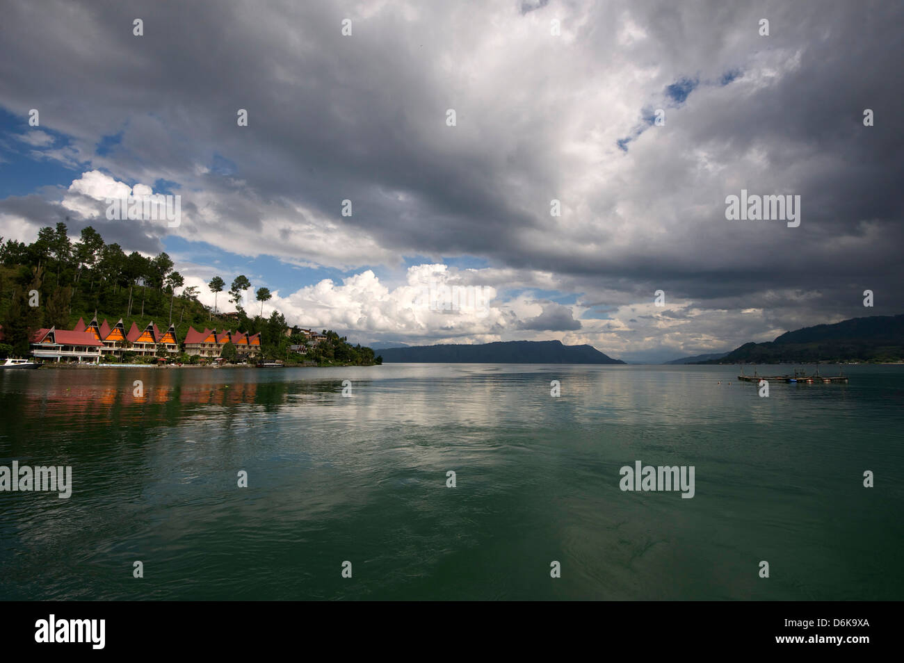Nuvole di monsone raccolta su hotel sul bordo delle acque cristalline del lago vulcanico di Toba, Sumatra Foto Stock
