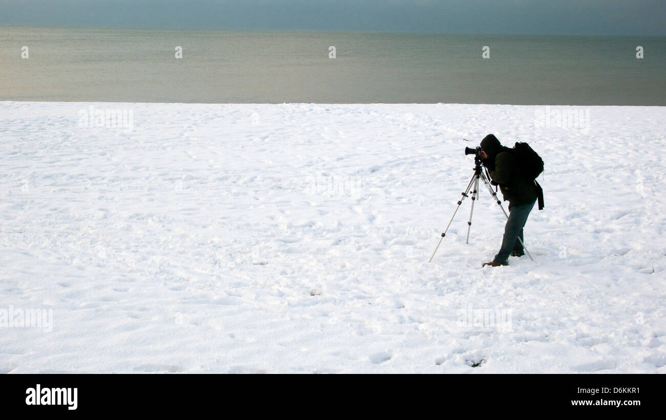 Fotografo con treppiede nella neve, Spiaggia di Brighton Regno Unito Foto Stock