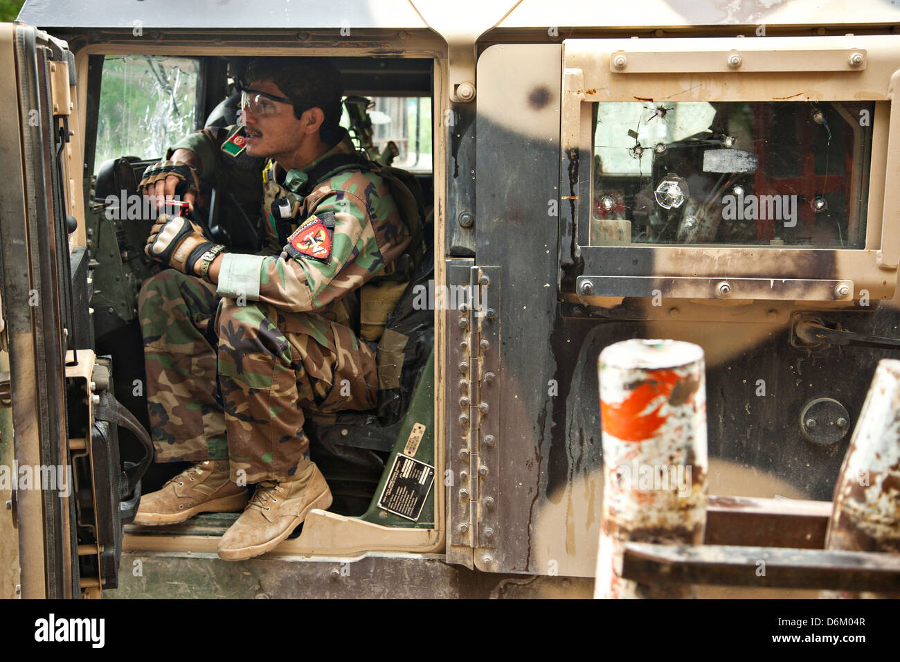 Un esercito nazionale afghano delle forze speciali soldato fornisce la sicurezza mentre Afghan agenti di polizia locali si incontrano con un ministero degli Interni del team di elaborazione 12 aprile 2013 nella provincia di Helmand, Afghanistan. Foto Stock