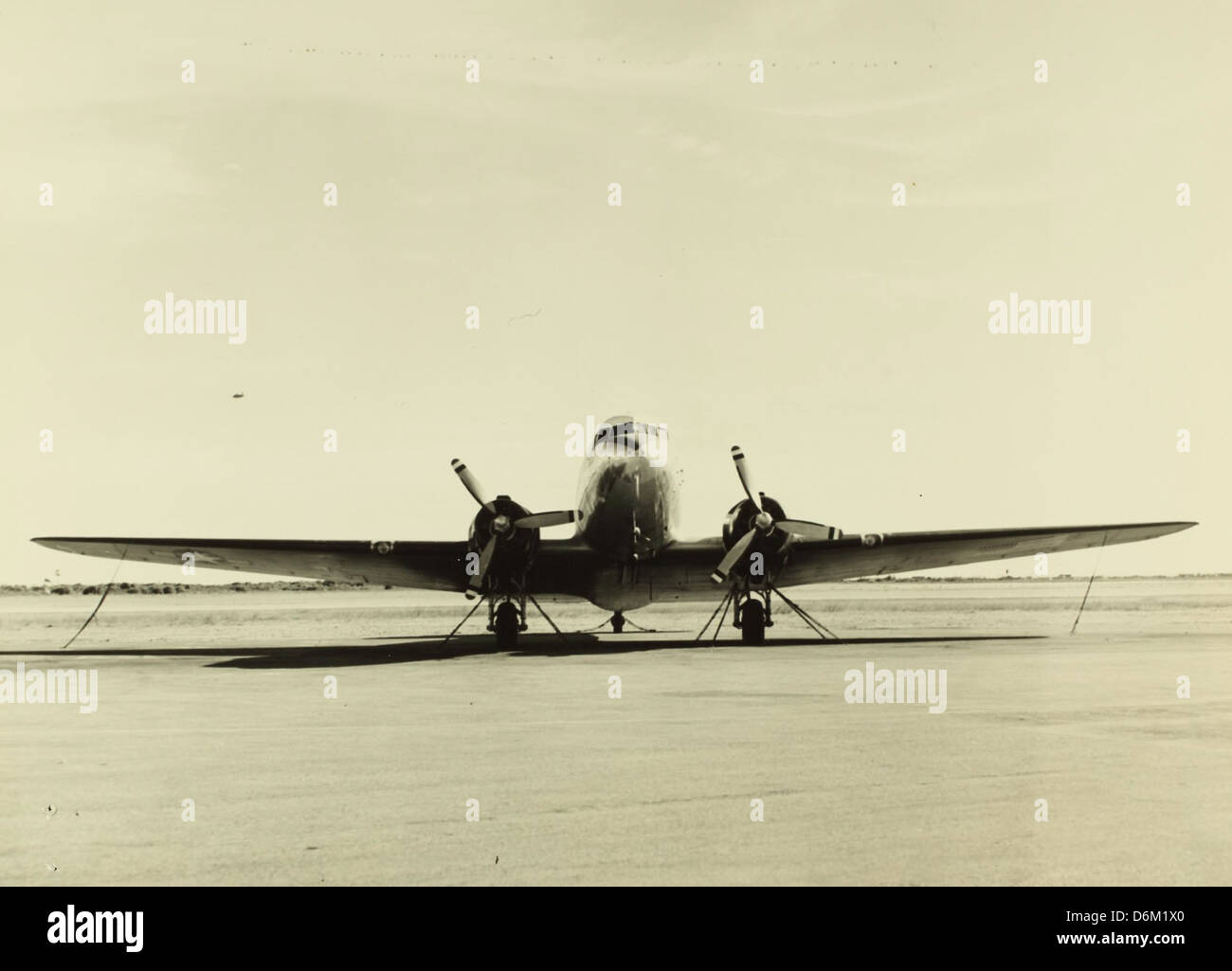 Questa foto mostra la procedura standard di ancoraggio per l'aeromobile R4D, una pratica fondamentale per garantire la sicurezza dell'aeromobile durante le operazioni a terra, in particolare per l'aviazione navale. Foto Stock