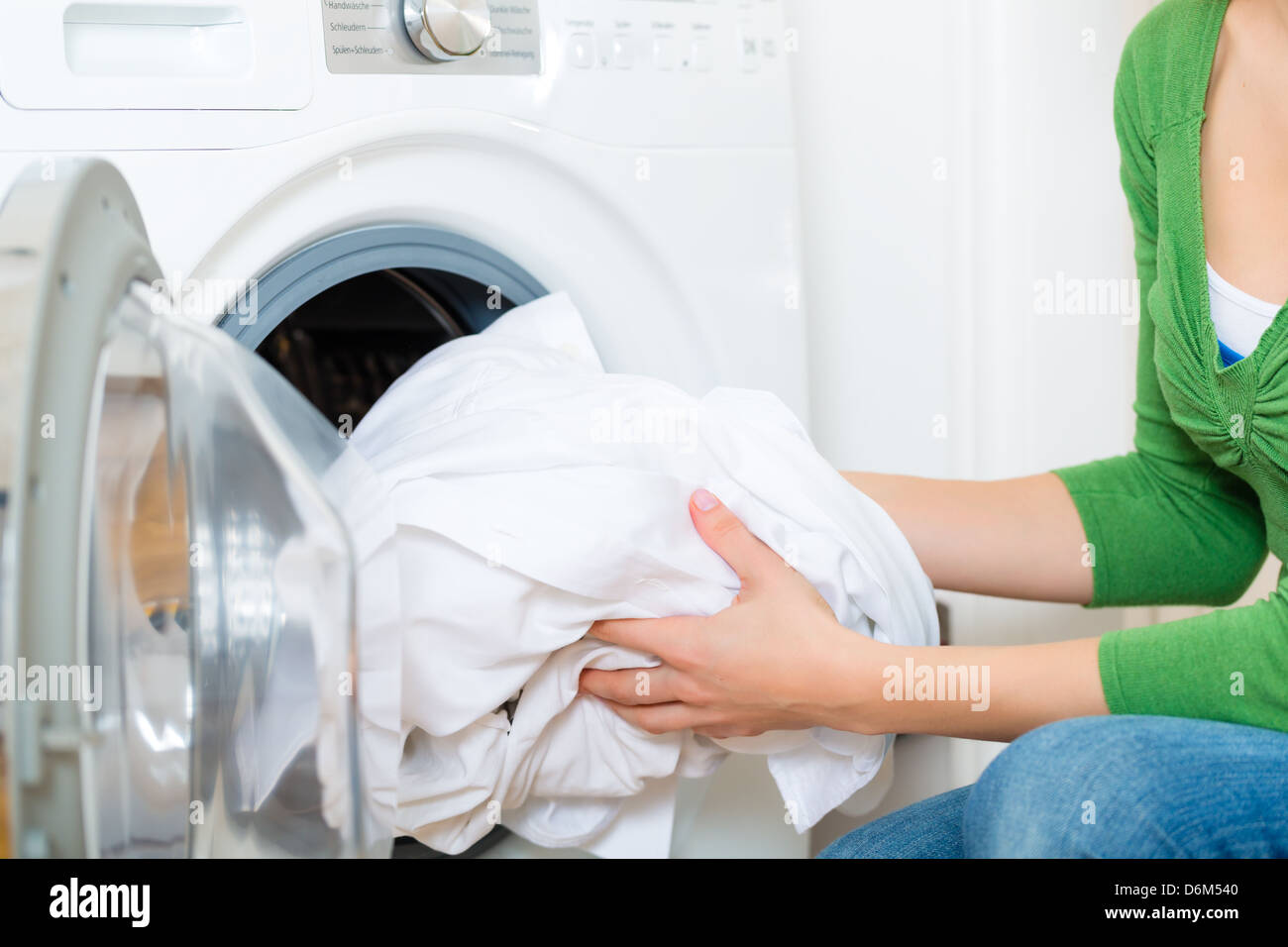 Giovane donna o governante dispone di un servizio lavanderia giornata a casa, lei prende il servizio lavanderia o bianchi al di fuori della vostra lavatrice o asciugatrice Foto Stock