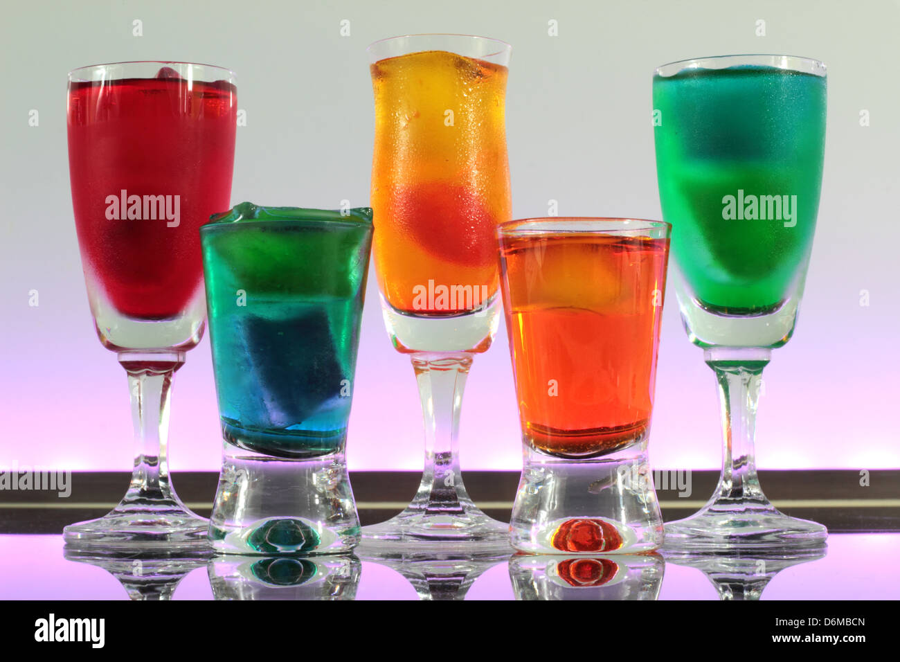 Dettaglio di una linea di cocktail colorati in appoggio sulla barra con illuminazione a led in un club Foto Stock