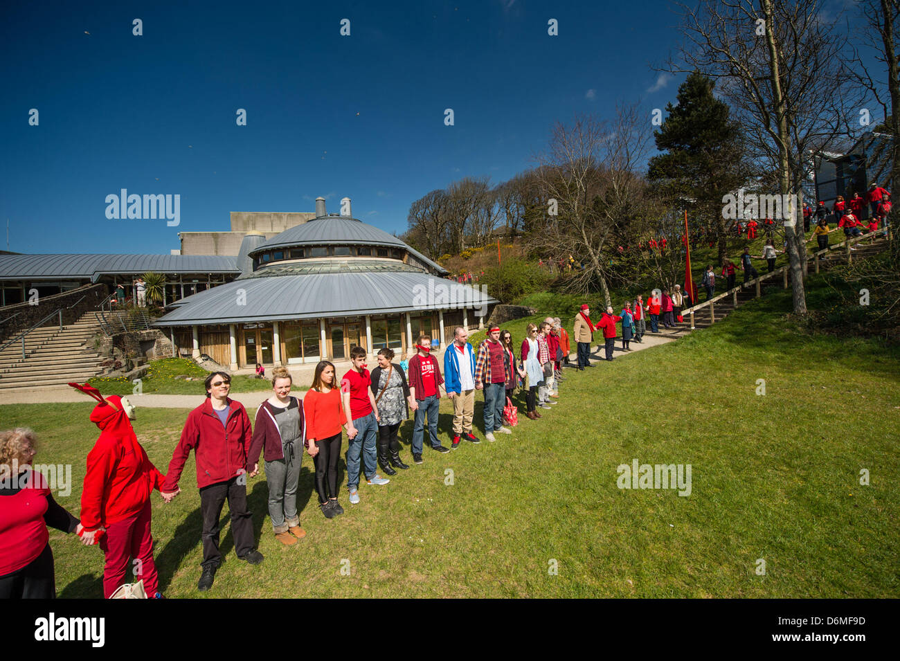 Aberystwyth Wales UK. Xx Aprile, 2013. Oltre 600 persone si sono radunate per circondare Aberystwyth Arts Center in una veglia silenziosa a metà giornata di oggi a sostegno dei sospesi i membri del personale e in segno di protesta per presunte minacce internazionalmente rinomato centro a seguito della ristrutturazione a Aberystwyth University. A seguito di una campagna su Facebook molte delle persone in veglia indossavano rosso, e alcuni di essi avevano gags oltre le loro bocche, per evidenziare la presunta "gagging ordini" che sono state applicate per i membri del personale del centro per impedire loro di commentare la situazione. Credito: Keith Morris/Alamy Liv Foto Stock