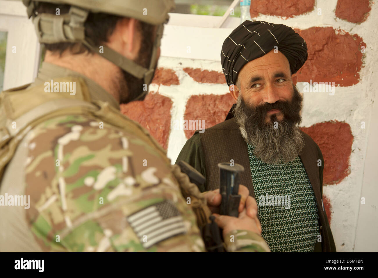 Una delle forze speciali degli Stati Uniti parla soldato con il governatore di distretto durante una pattuglia con l esercito nazionale afgano forze speciali Aprile 14, 2013 nella provincia di Helmand, Afghanistan. Foto Stock