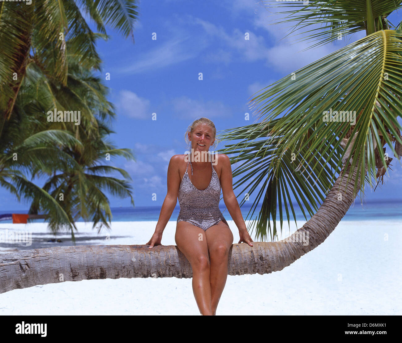 Giovane donna seduta su Palm tree, Kuda Bandos, Bandos Island, Kaafu Atoll, Repubblica delle Maldive Foto Stock