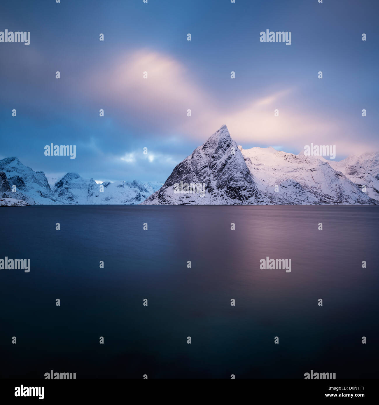 Alba invernale sulla neve coperto Olstind picco di montagna che salgono dal fiordo, Toppøya, Moskenesøy, Isole Lofoten in Norvegia Foto Stock