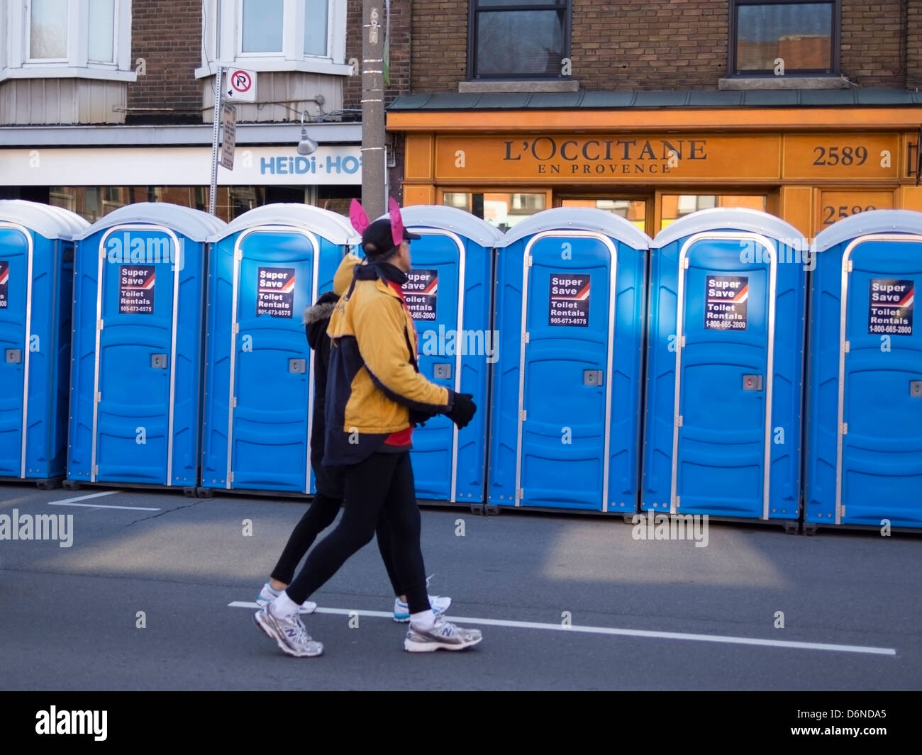 Un ritmo bunny con orecchie rosa passeggiate passato blu bagni portatili davanti al 2013 Toronto Yonge Street 10K gara di corsa. Foto Stock