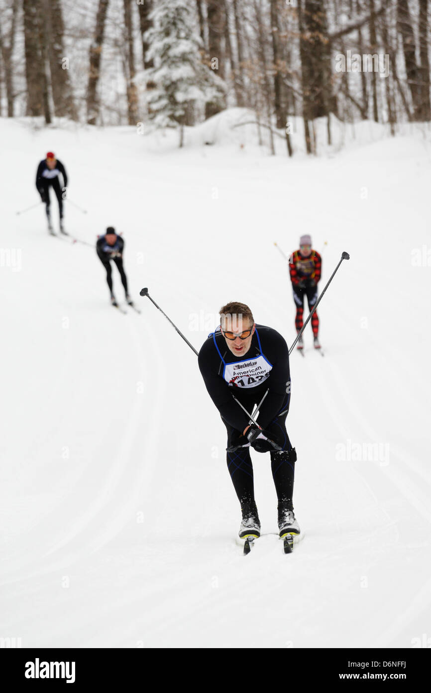 Stile classico sciatori tuck e scivolano in discesa sul sentiero tra cavo e Hayward, WI durante l'American Birkebeiner. Foto Stock