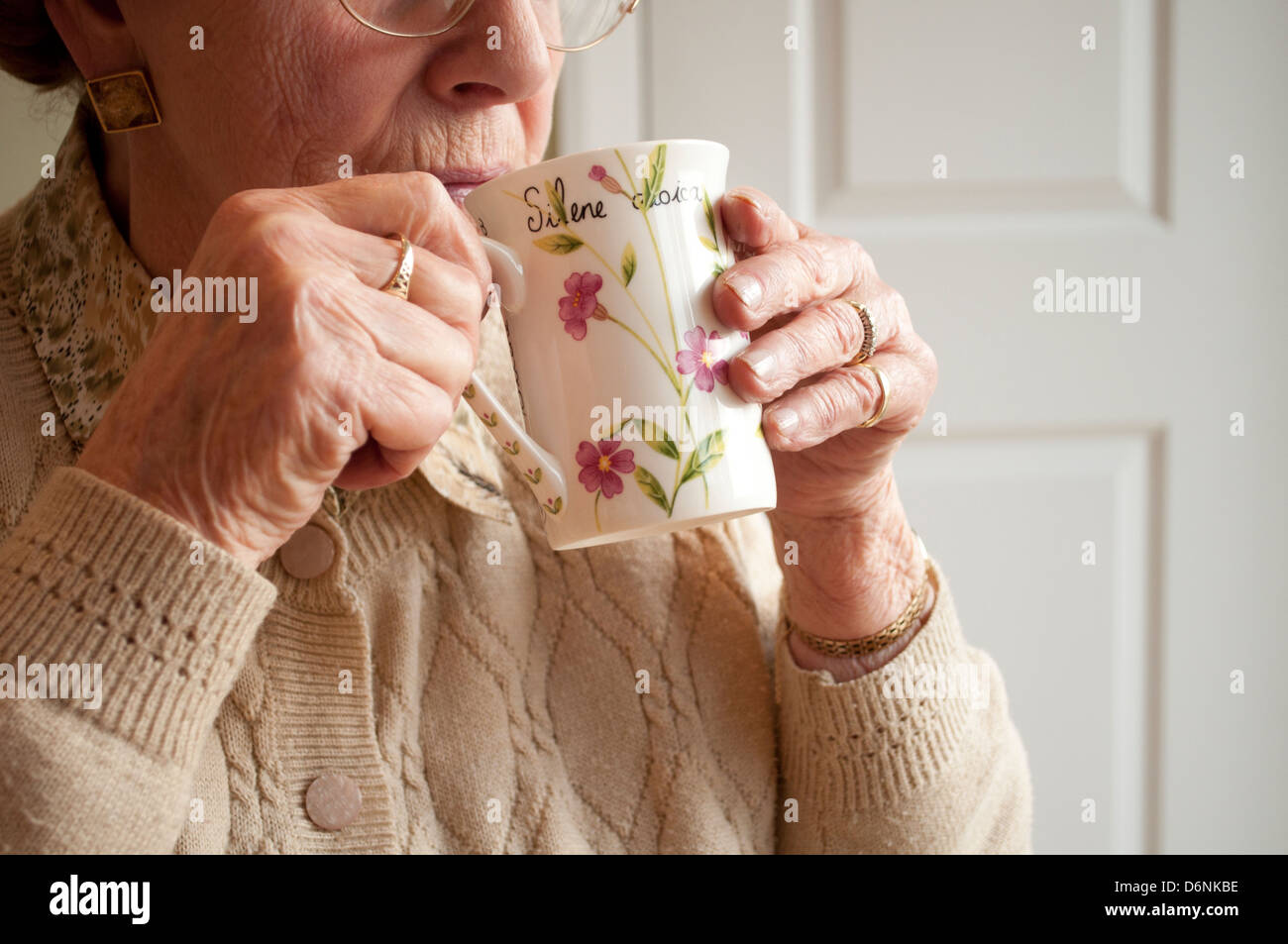 Donna anziana bevande tè guardando fuori della finestra Foto Stock