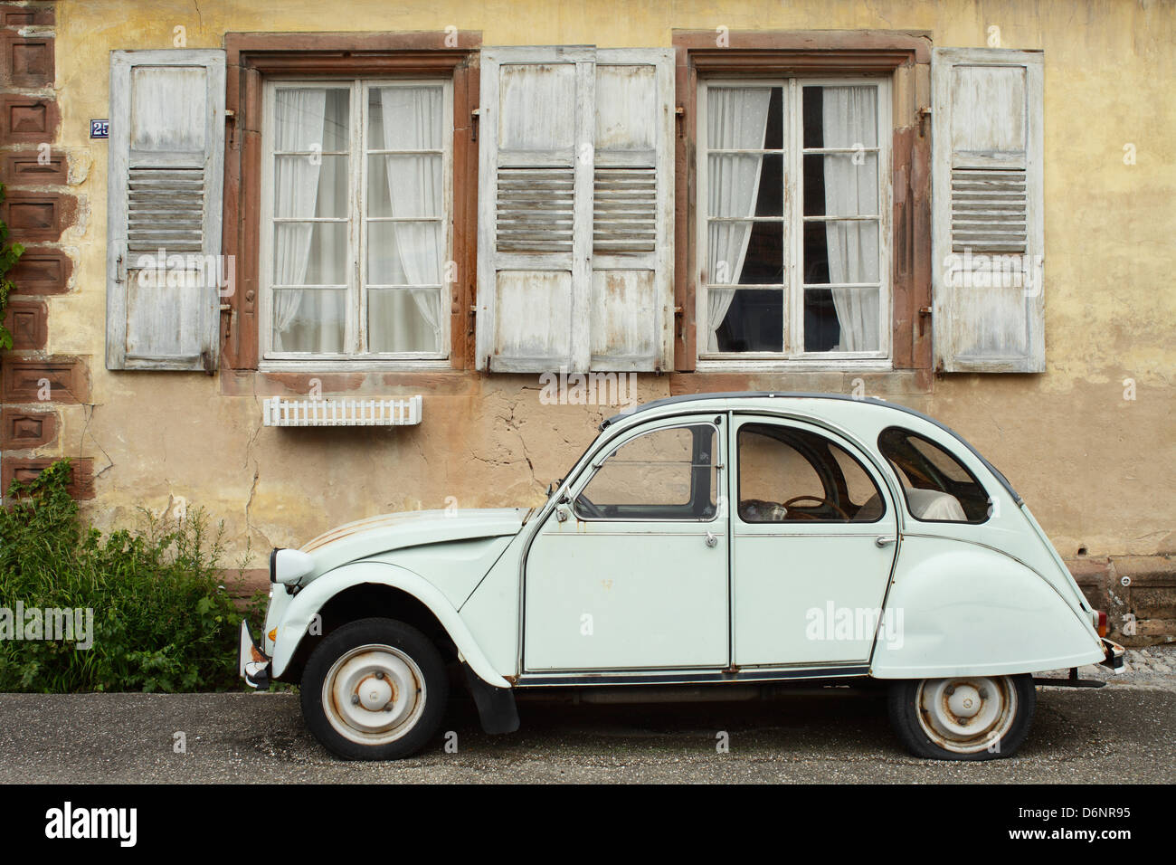 Wissembourg, Francia, Citroen 2 CV con un pneumatico a terra di fronte a un vecchio edifici residenziali Foto Stock