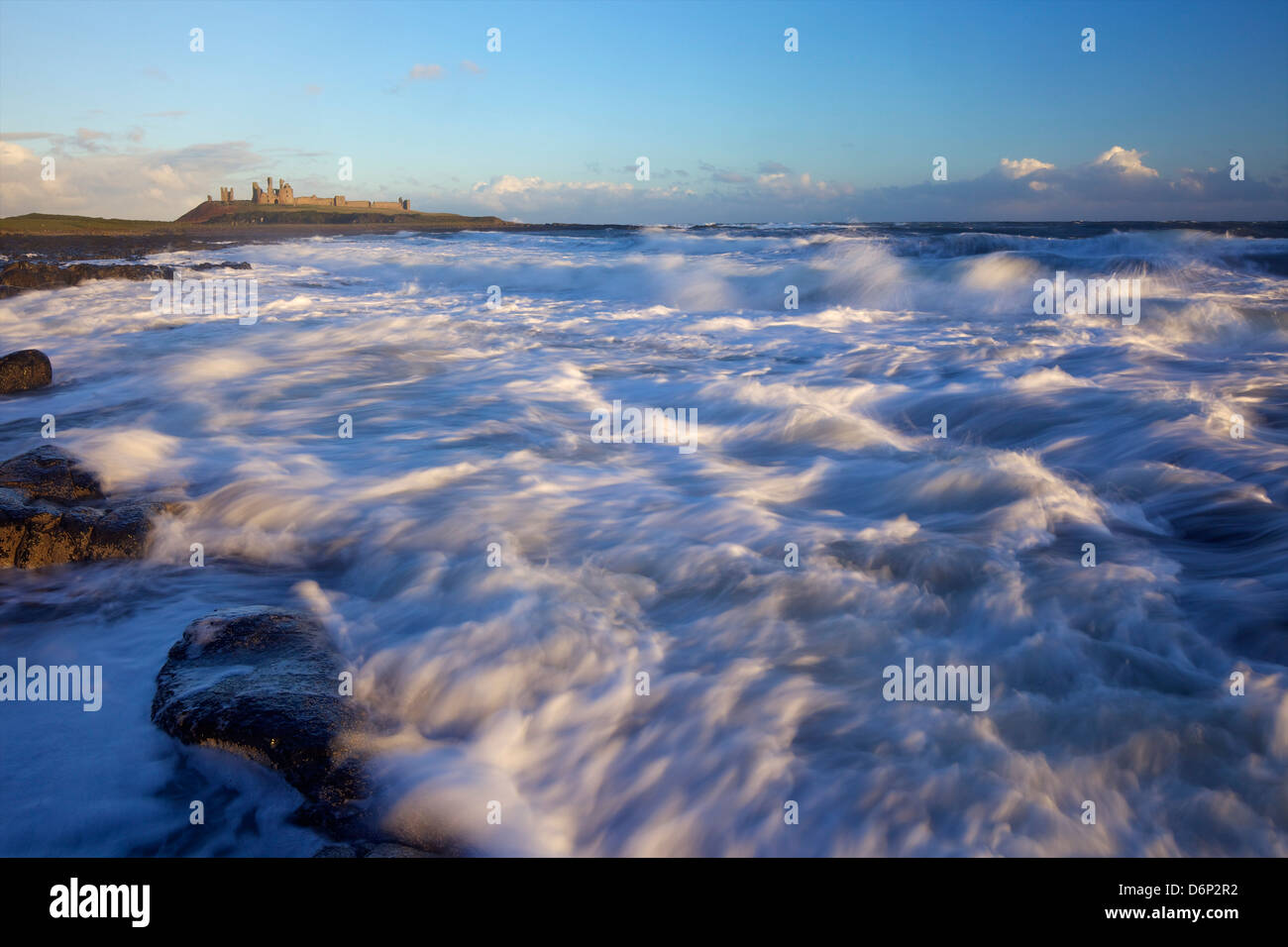 Surf sulle rocce, Dunstanburgh Castle, Northumberland, England, Regno Unito, Europa Foto Stock