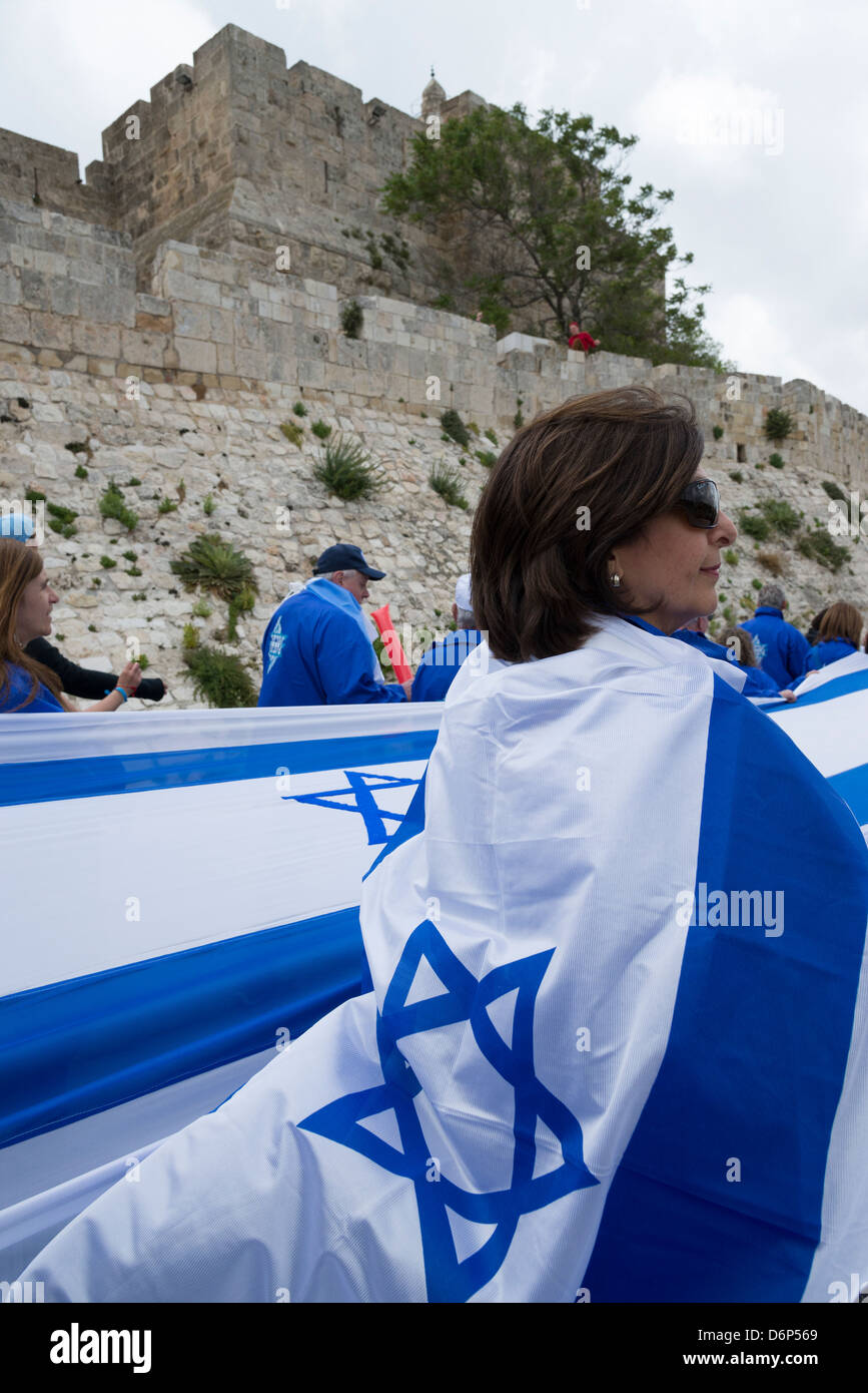 Folla in marcia con una lunga bandiera israeliana intorno alle mura della citta'. Gerusalemme la città vecchia. Israele. Foto Stock