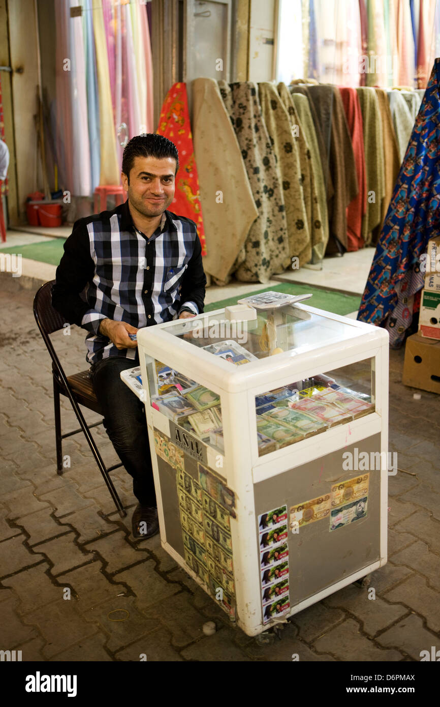 Un uomo seduto e in attesa per il business lo scambio di denaro e acquisto di valuta estera in un dispositivo mobile cambio valuta all'interno della vecchia Foto Stock
