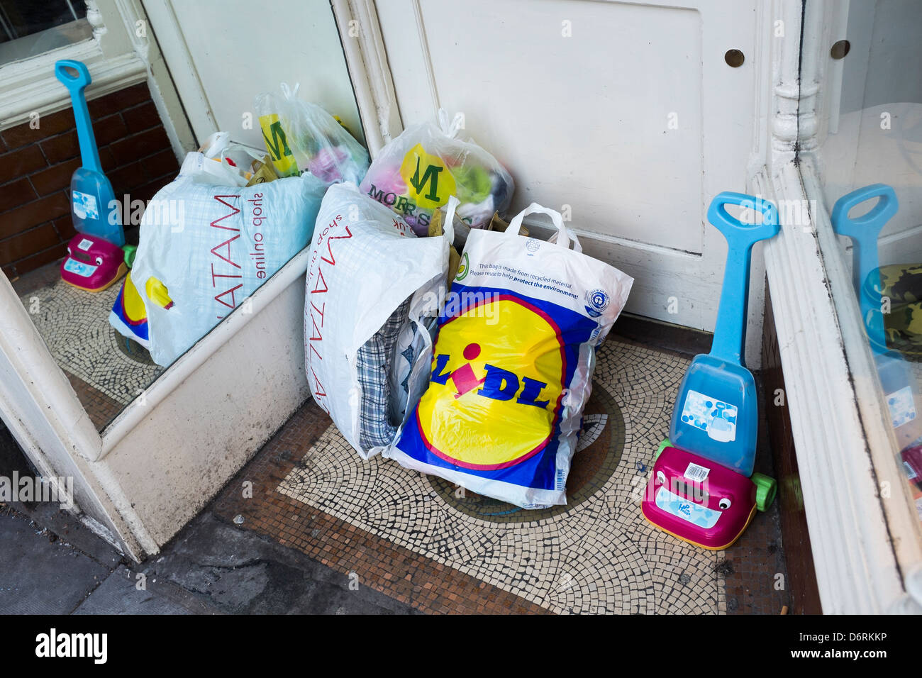 Sacchetti di beni donati a sinistra al di fuori di un ramo di Oxfam carità shop, REGNO UNITO Foto Stock