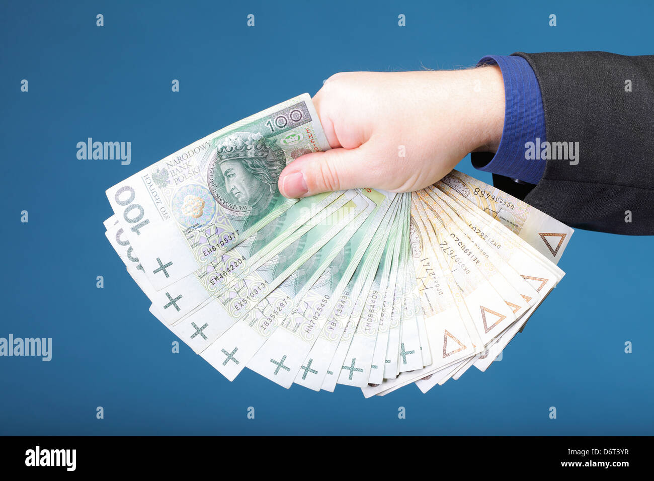 Imprenditore il mano azienda polacca di banconote denaro sfondo blu Foto Stock