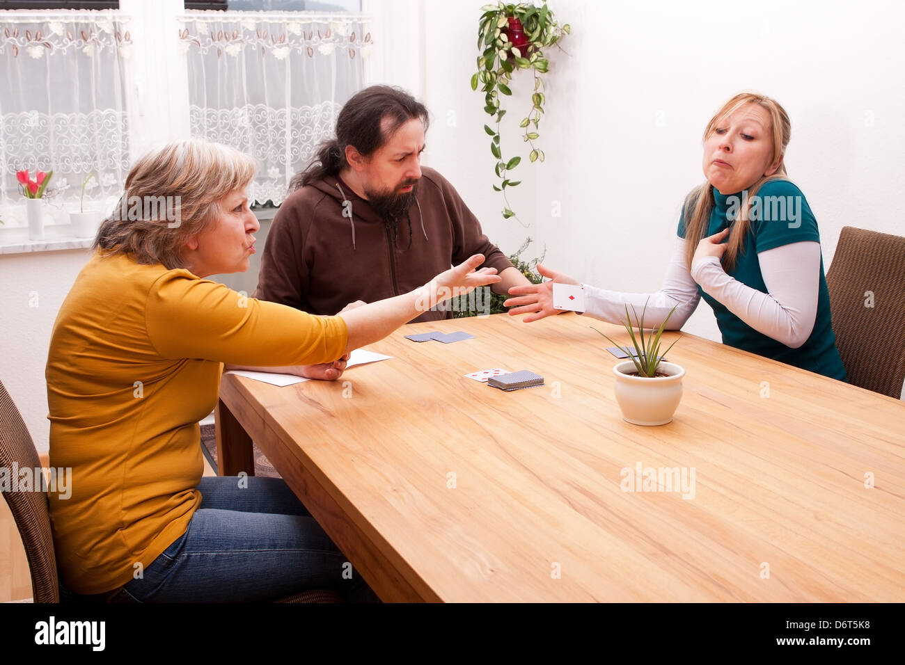 La bionda figlia barare in giochi di carte con la famiglia Foto Stock