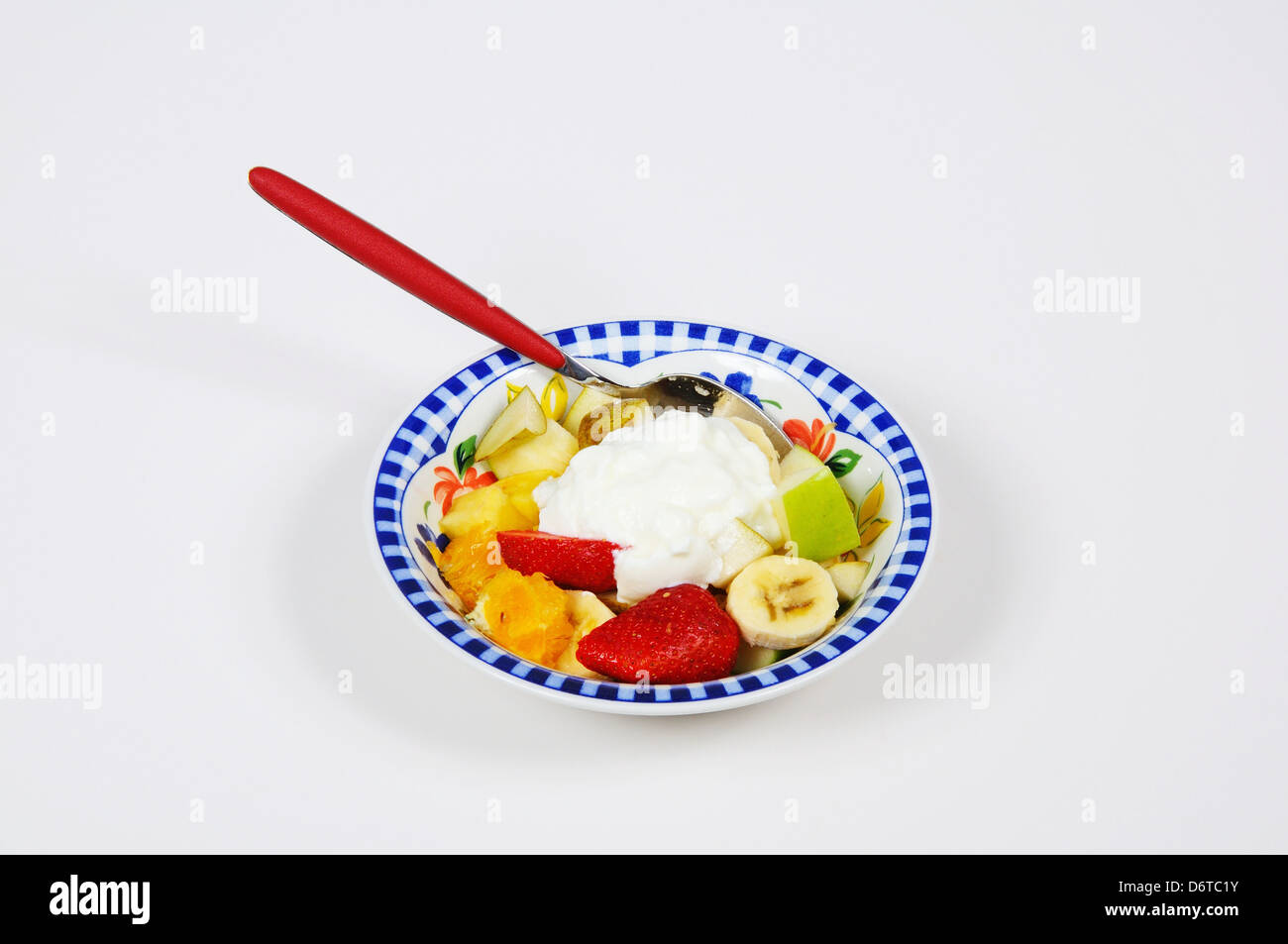 Ciotola di insalata di frutta con yogurt contro uno sfondo semplice. Foto Stock