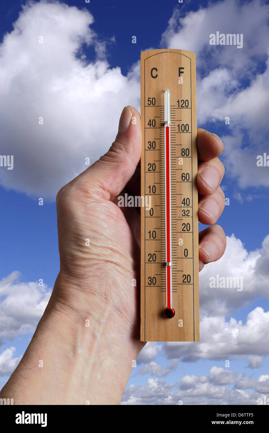 Mano che tiene un termometro che indica il cambiamento climatico a causa dell aumento delle temperature su scala mondiale. Foto Stock