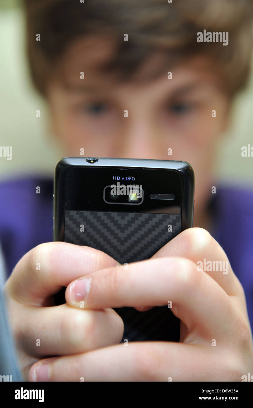 Ragazzo di dodici anni utilizza il suo telefono mobile per il social networking modello rilasciato Foto Stock