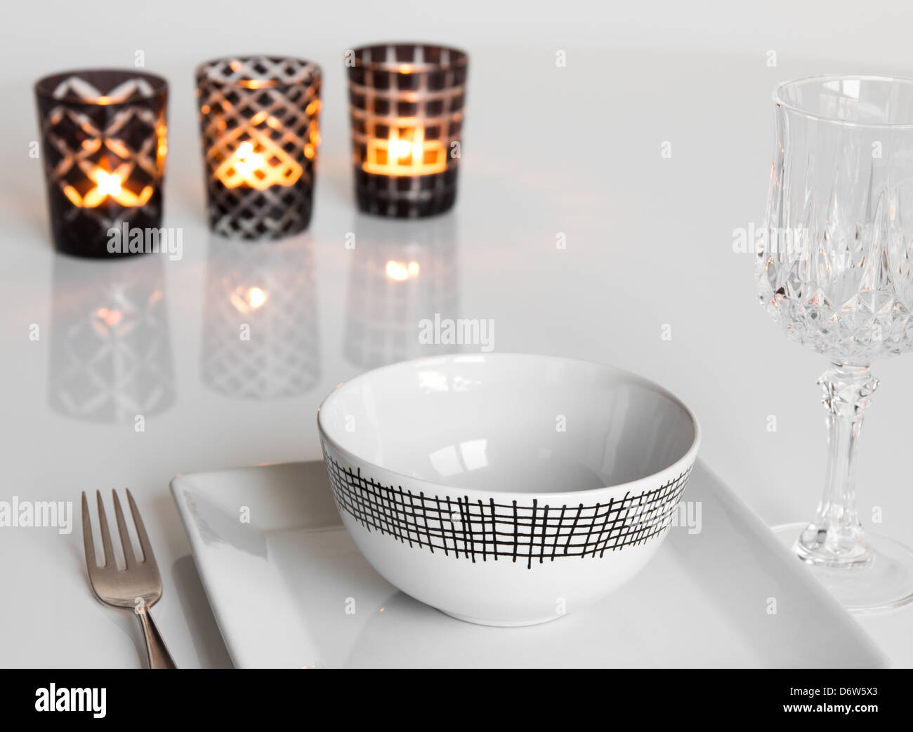 Tabella semplice impostazione con tre candele in vetro portacandele. Foto Stock