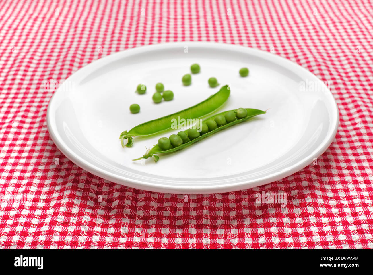 Materie piselli sul piatto di portata in ceramica bianca servita sul tavolo da cucina. Dietologia e mangiare sano concetto. Foto Stock