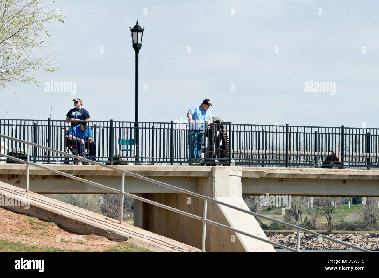 Tre uomini caucasici pesce da cima a piedi sulla diga Overholser nella città di Oklahoma, Oklahoma, Stati Uniti d'America area su un inizio di giornata di primavera. Foto Stock