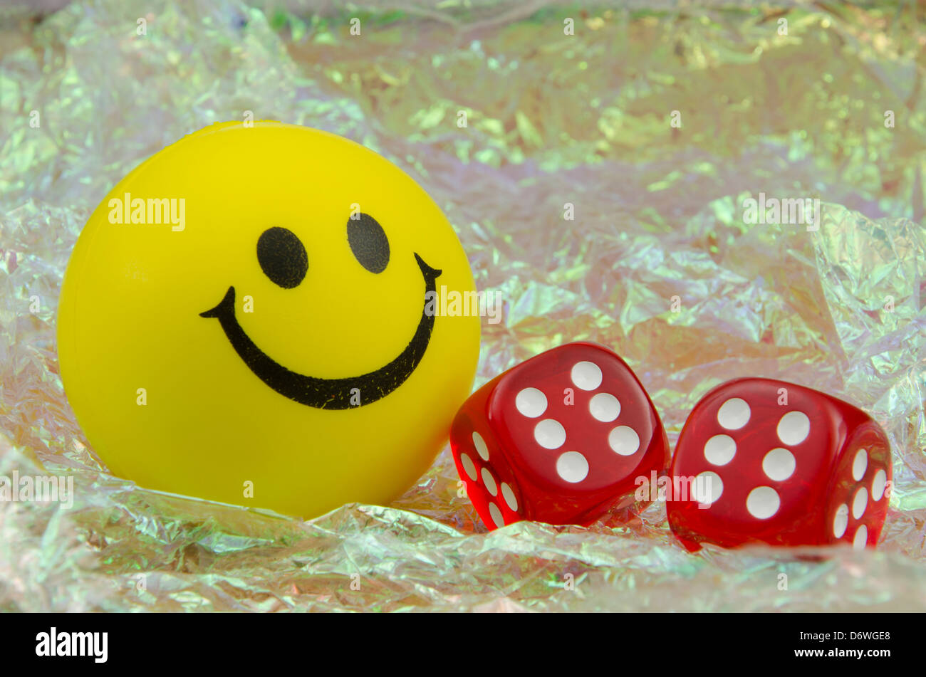Felice giallo Smiley face con una coppia di dadi rossi che mostra un rotolo di dodici, su un brillante sfondo perlato Foto Stock