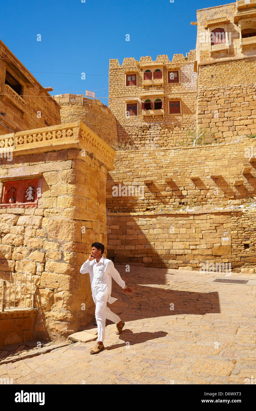 Scena di strada con india uomo vestito di bianco parlando al telefono cellulare, Jaisalmer Fort, Rajasthan, India Foto Stock