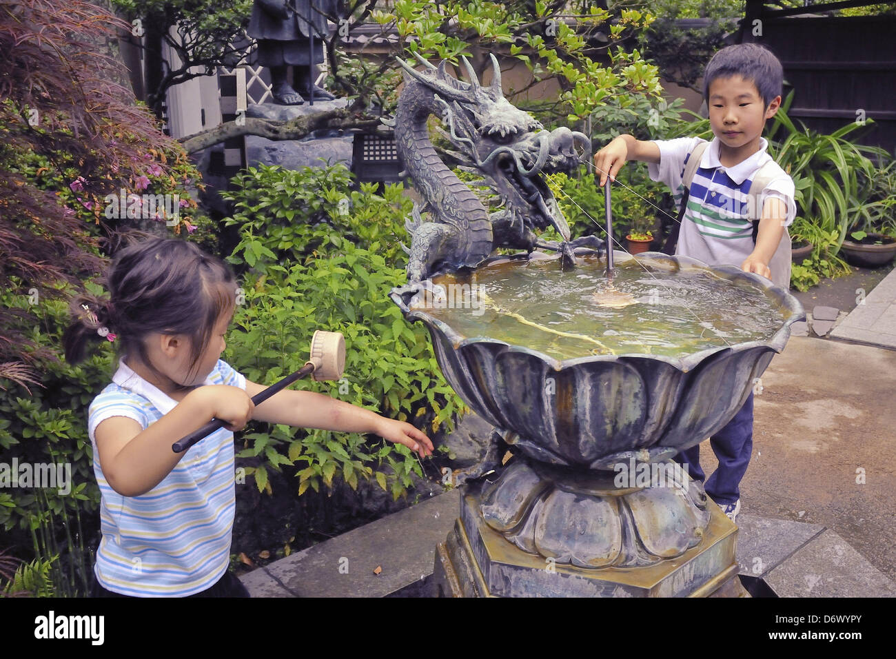 Kamakura, Giappone - 21 Giugno 2008: bambini giapponesi di lavare le mani in tradizionale fonte di acqua prima di entrata al tempio buddista Foto Stock