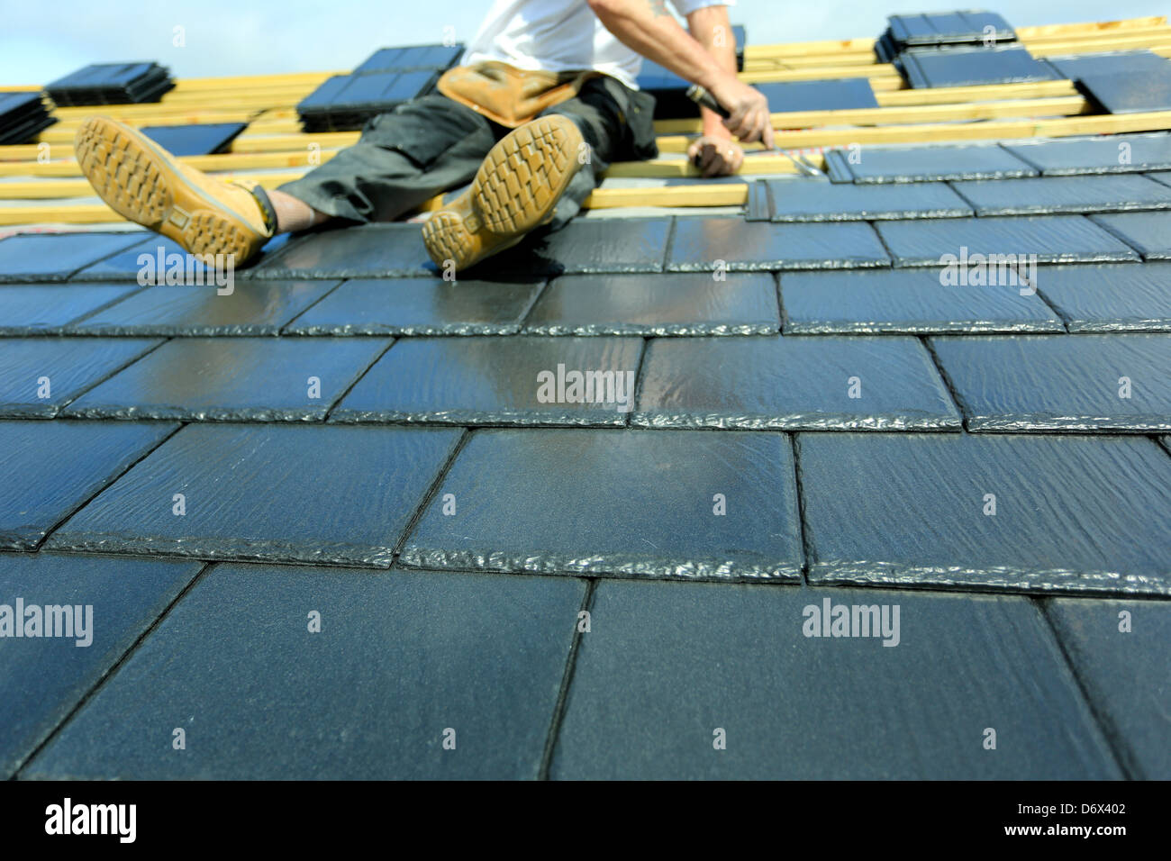Costruzione ha lavorato il montaggio piastrelle per il nuovo tetto della casa Foto Stock