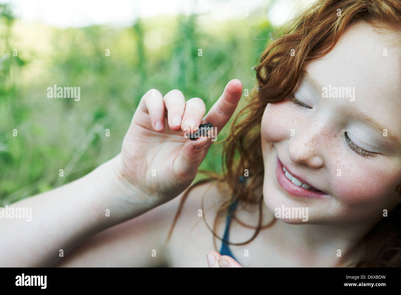 9 anno vecchia ragazza tenendo piccolo rospo Foto Stock