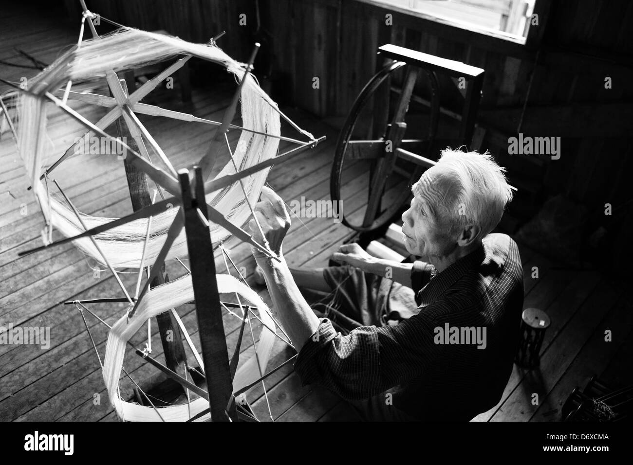 Il vecchio uomo di seta di filatura sul vecchio stile ruota di filatura in MYANMAR Birmania Foto Stock