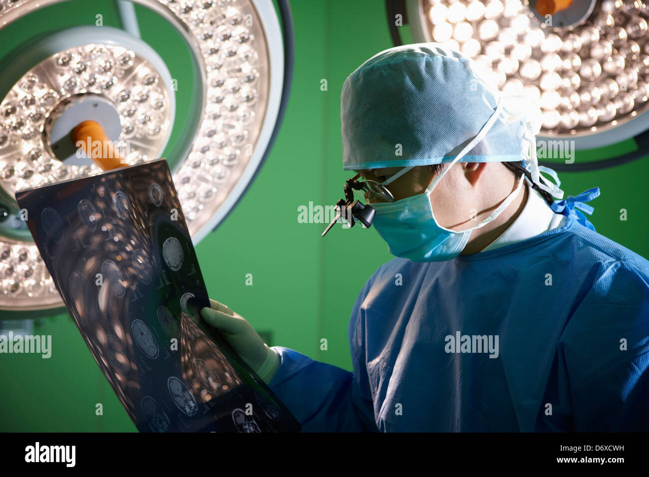 Un chirurgo che indossa un medico occhiali loop tenendo premuto x ray immagine Foto Stock