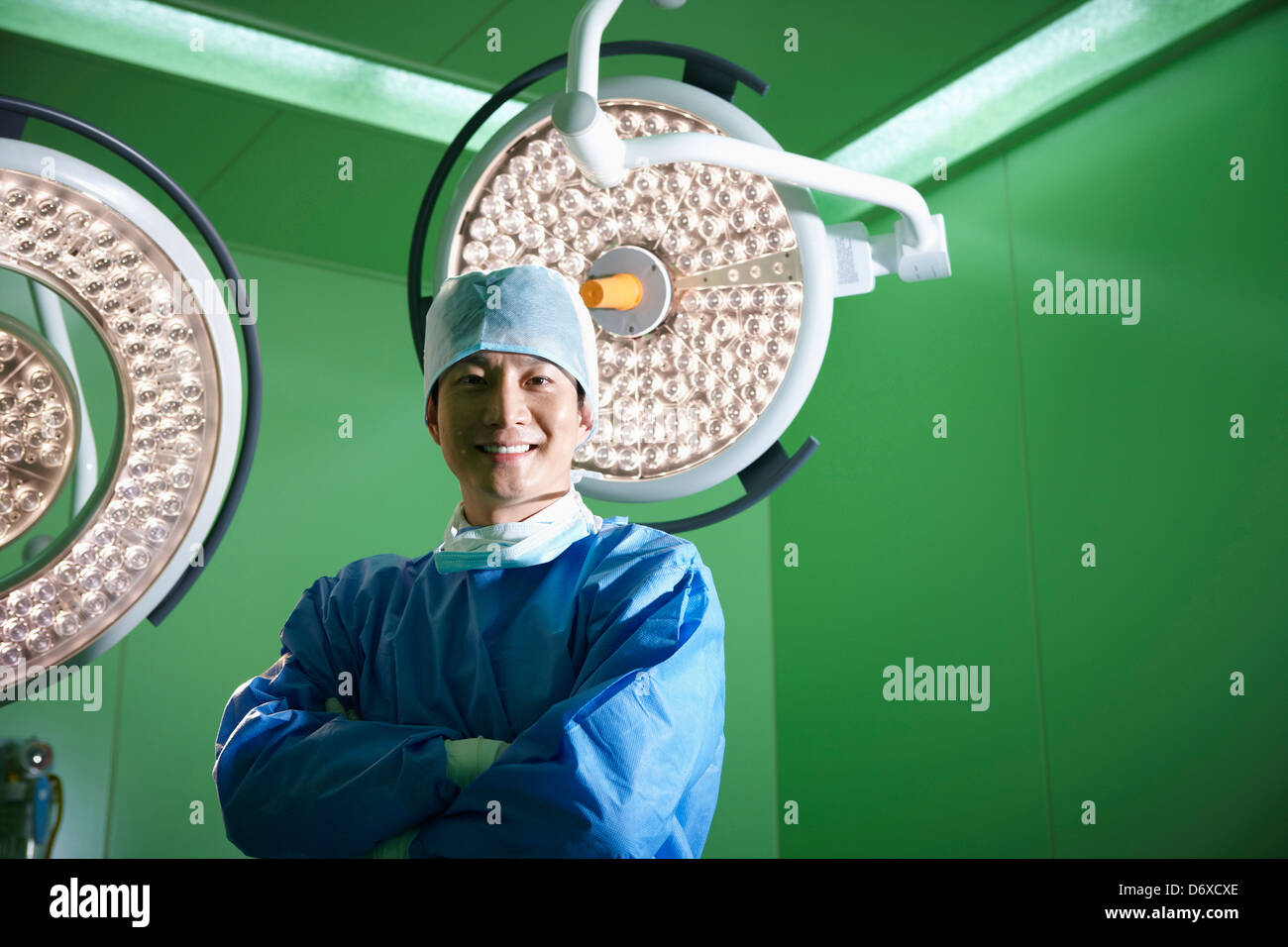 Un giovane chirurgo in piedi nella camera operativa con le braccia incrociate Foto Stock