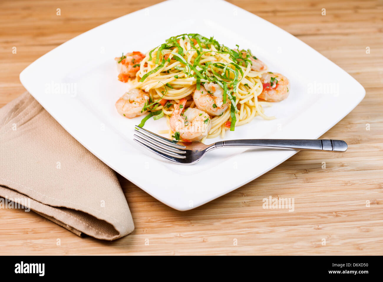 Closeup foto orizzontale di un piatto di pasta con gamberi grandi, basilico, prezzemolo, acciaio inossidabile la forcella e il panno assorbente Foto Stock