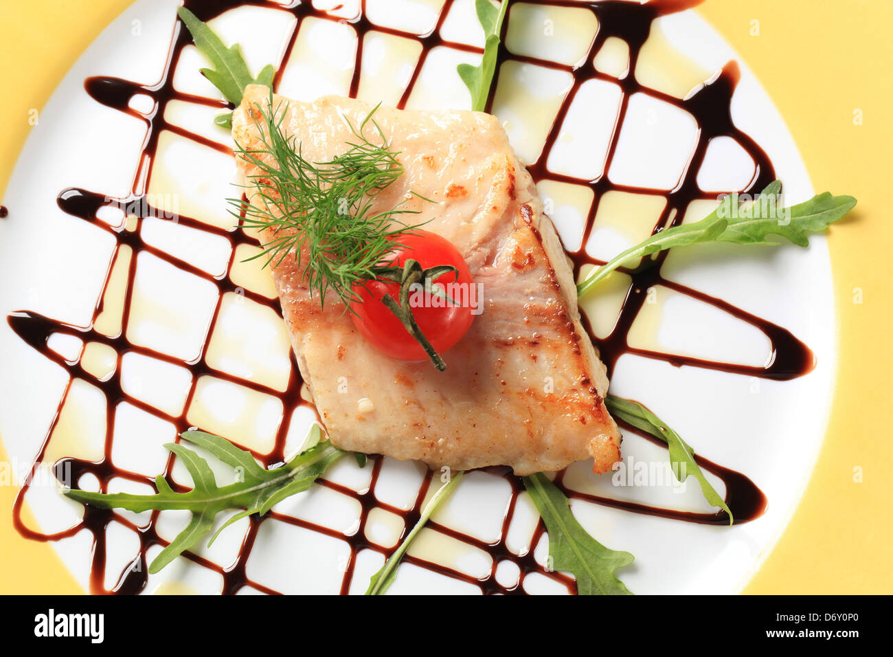 Pan disseccata filetto di pesce guarnito con foglie di rucola e aceto balsamico Foto Stock