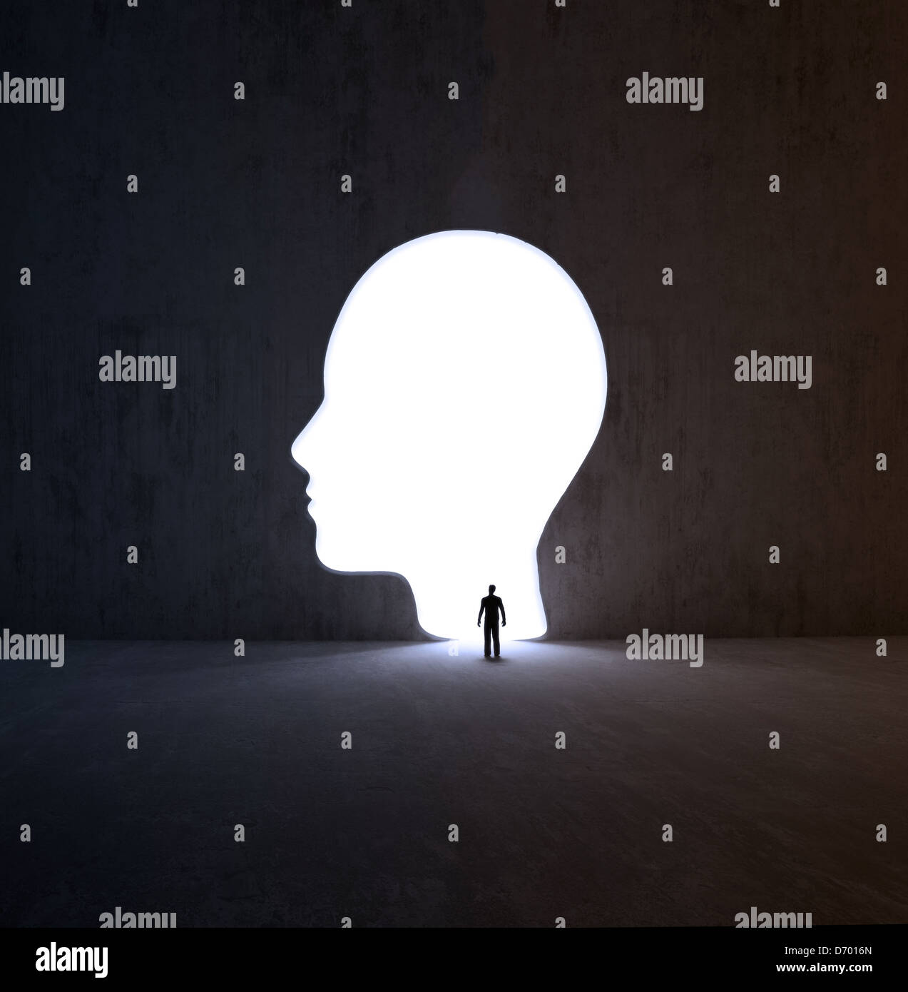 Un piccolo uomo a camminare in una testa sagomata di apertura in una parete Foto Stock