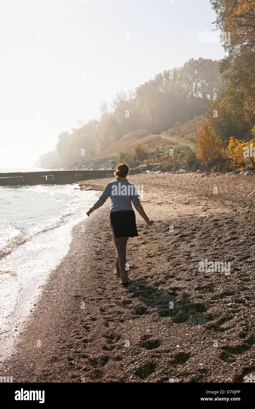 Una donna cammina da sola su un lago Michigan beach in autunno. Foto Stock