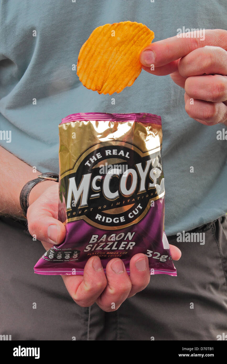Uomo caucasico di mangiare un sacco di pancetta McCoys sapore Ridge tagliare le patatine modello rilasciato Foto Stock