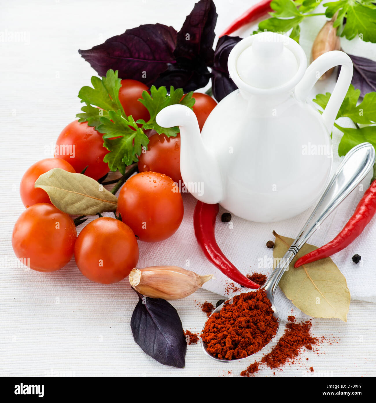 Pomodori freschi, le erbe aromatiche, le spezie e la brocca dell'olio su sfondo chiaro, il fuoco selettivo Foto Stock