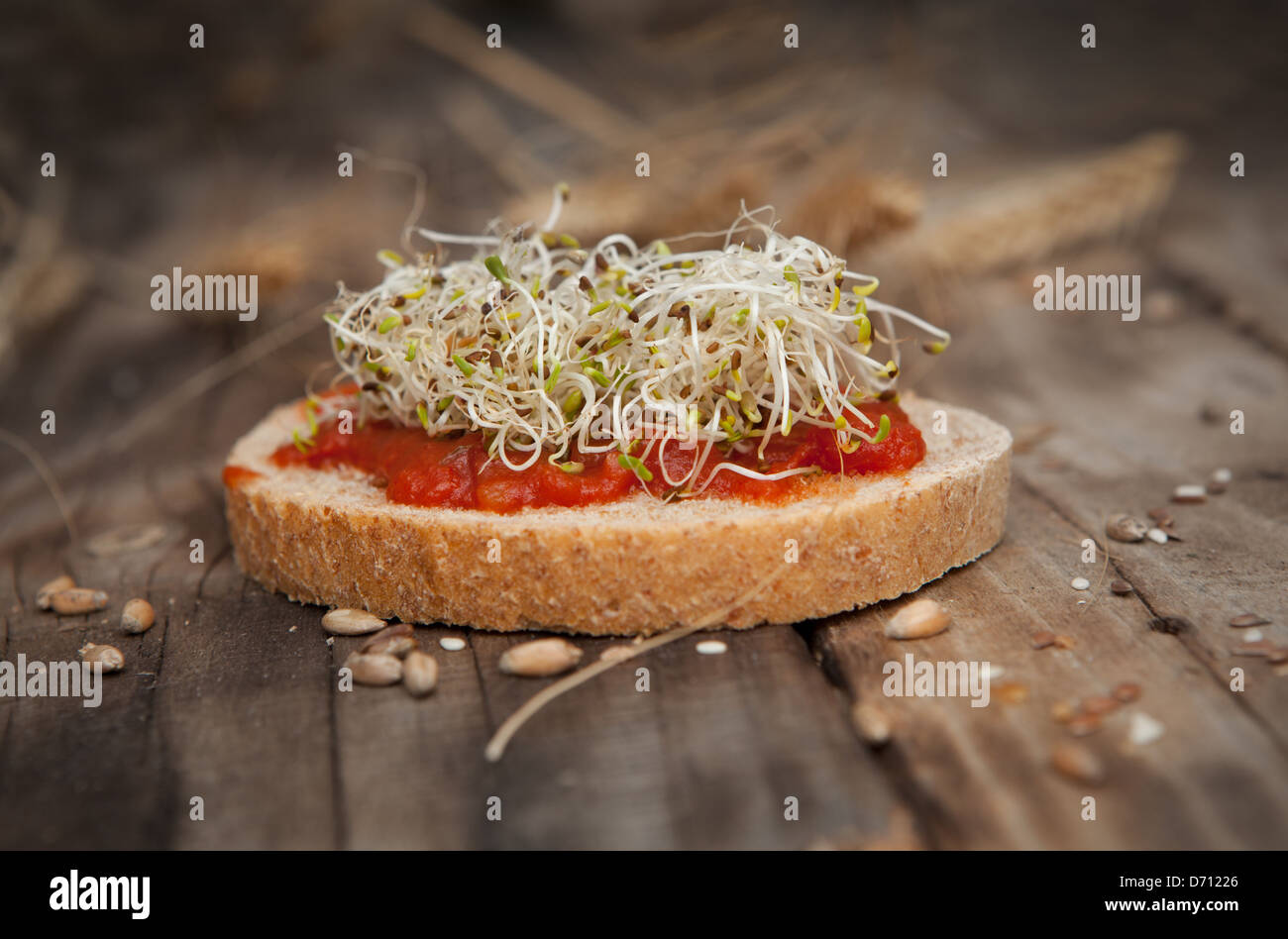Una fetta di pane con i germogli e i pomodori Foto Stock