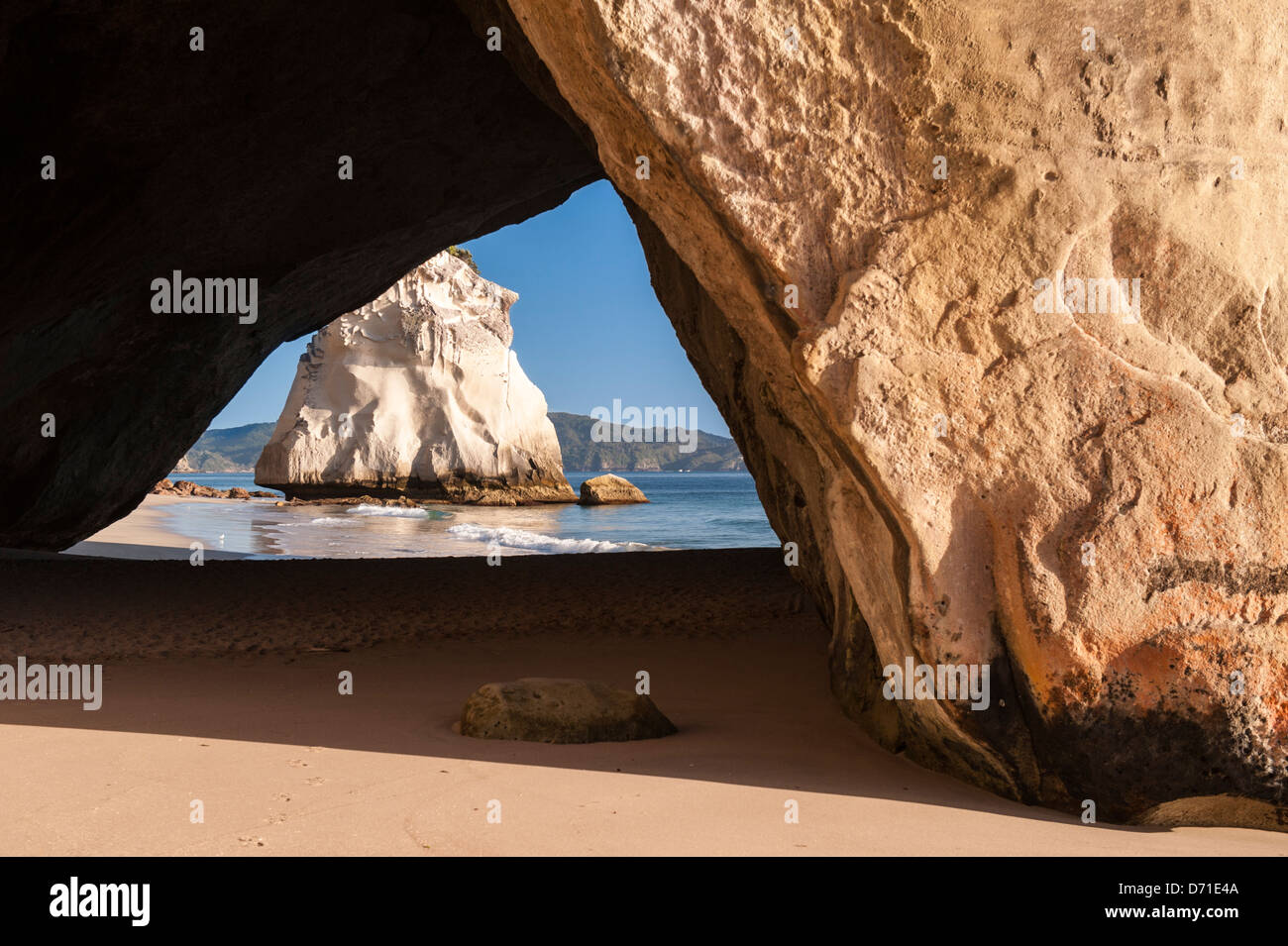 La suggestiva pietra calcarea naturale pila Te Hoho Rock visto attraverso la roccia arco in Cove della cattedrale, Penisola di Coromandel la mattina presto. Nuova Zelanda Foto Stock