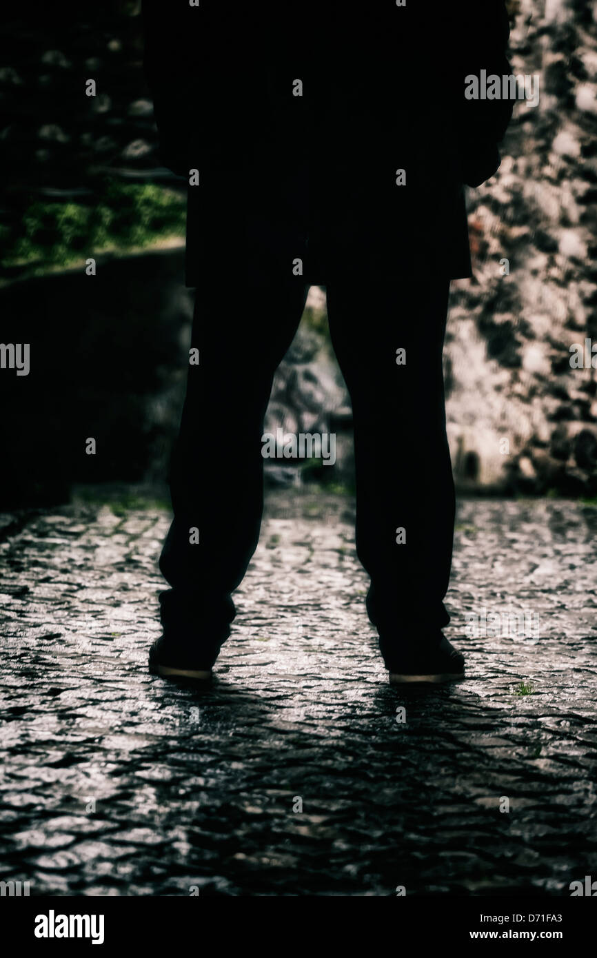 Le gambe di un uomo in un vicolo buio Foto Stock