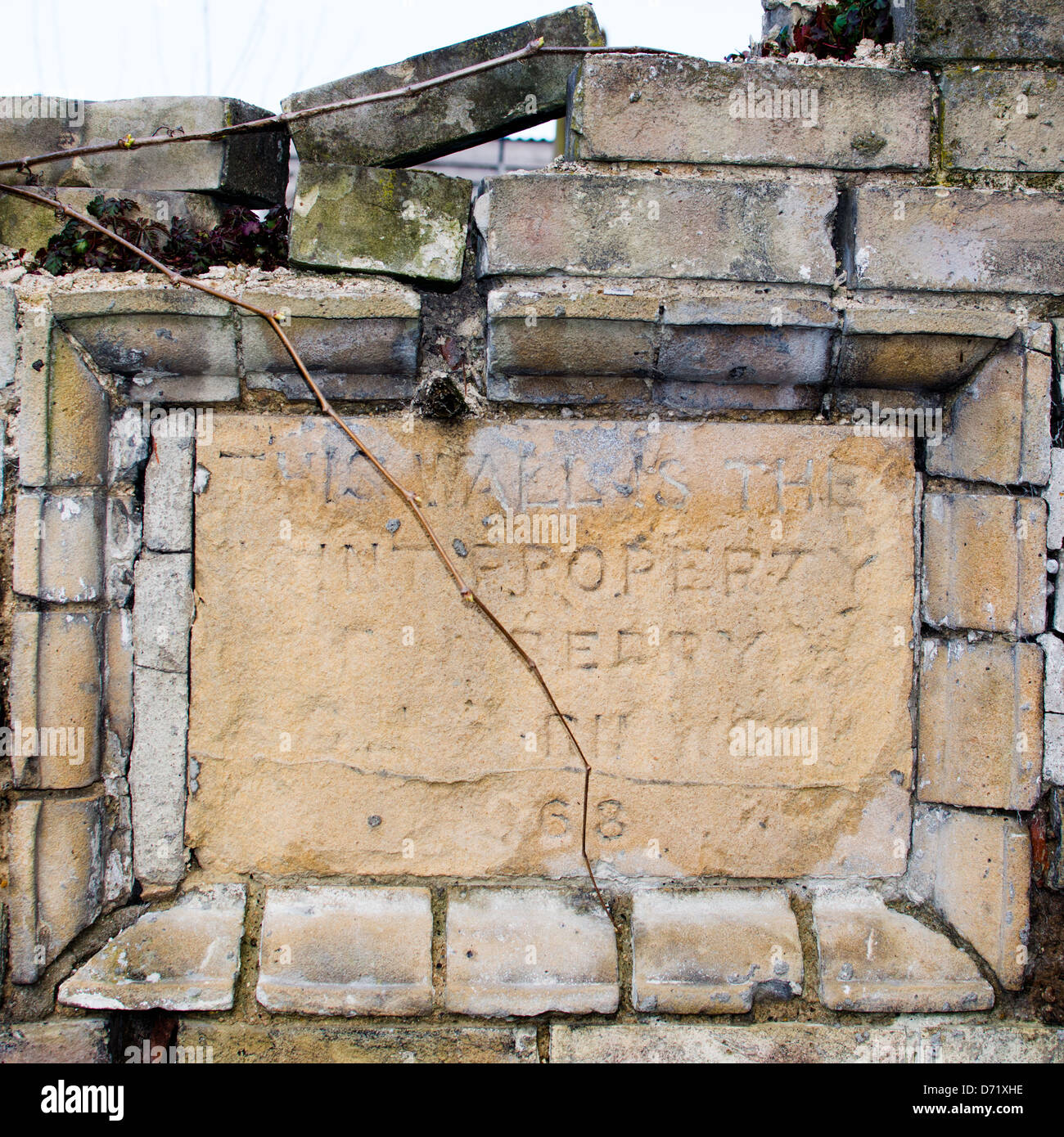 Una tavoletta di pietra impostato in un vecchio muro, segnando la parete di proprietà. La sbiadita suggerisce di iscrizione del XIX secolo. Foto Stock