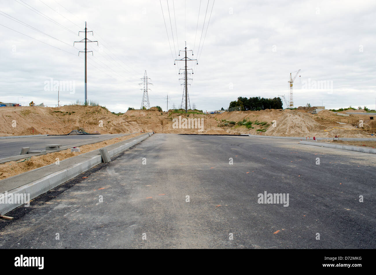 Costruzione di strada asfaltata in cantiere. Alta tensione linea di energia elettrica. Foto Stock