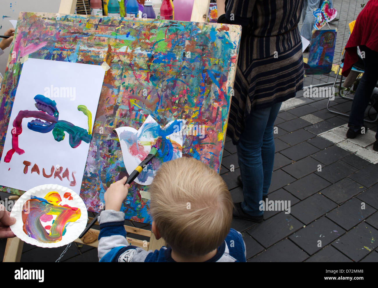 Kid disegnare quadri colorati con spazzola in outdoor street evento. Foto Stock