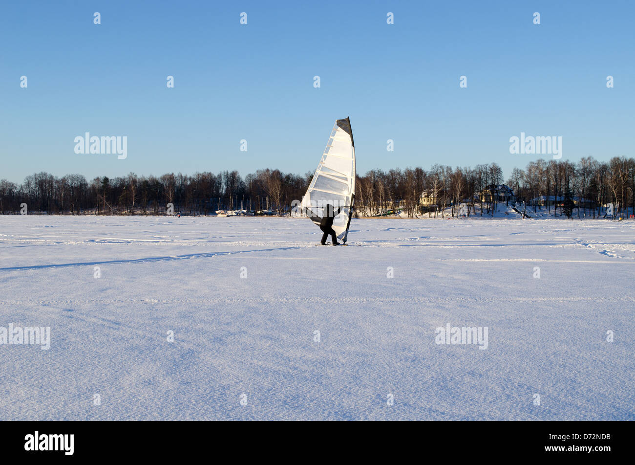 Il ghiaccio surfer uomo vento cattura la vela sul lago ghiacciato di neve. extreme sport stagionale. moderna attività ricreative hobby. Foto Stock