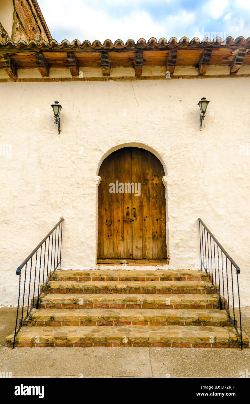 Un Coloniale in legno porta sul lato di una vecchia chiesa Foto Stock